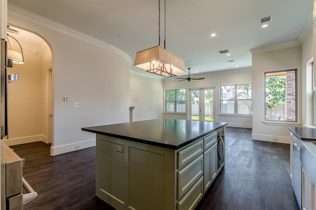 Custom kitchen island with painted shaker base, dark stone top, and a microwave drawer facing the living area