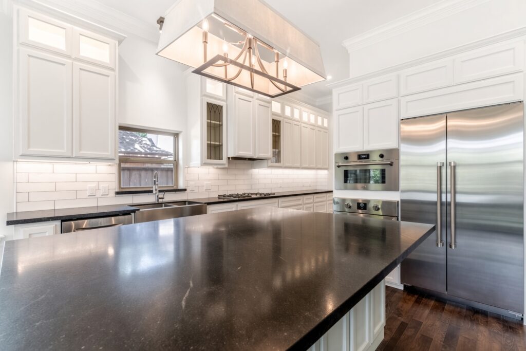 Custom kitchen remodel with white cabinets and dark granite island — Spring TX