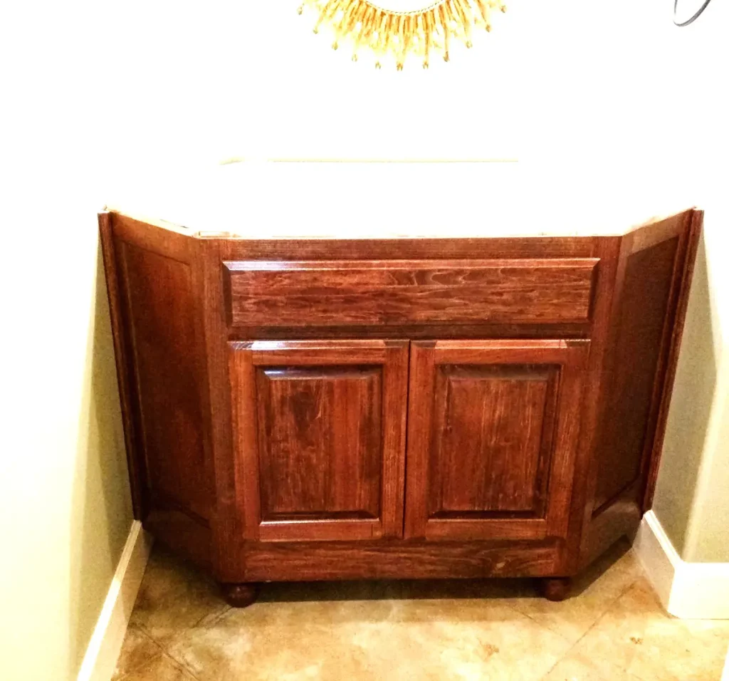 After — custom stained wood guest vanity built to angled walls, installed and waiting on the granite top.