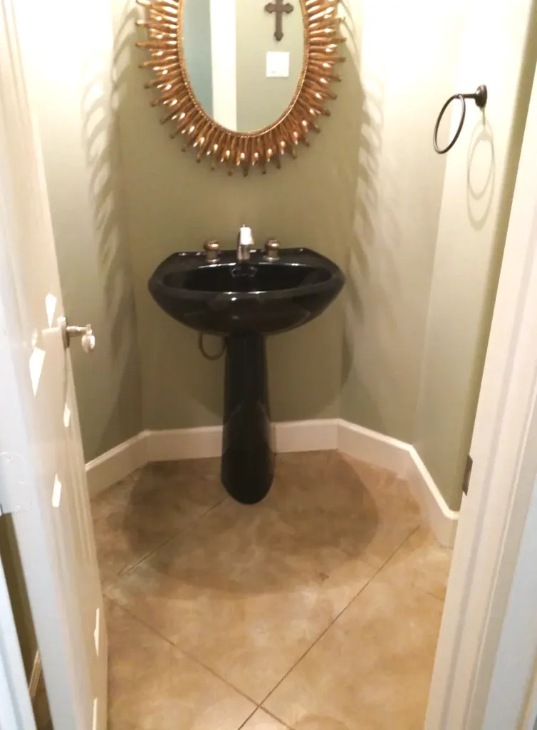 Before — guest bath with a black pedestal sink, no vanity, and walls that meet at an angle.