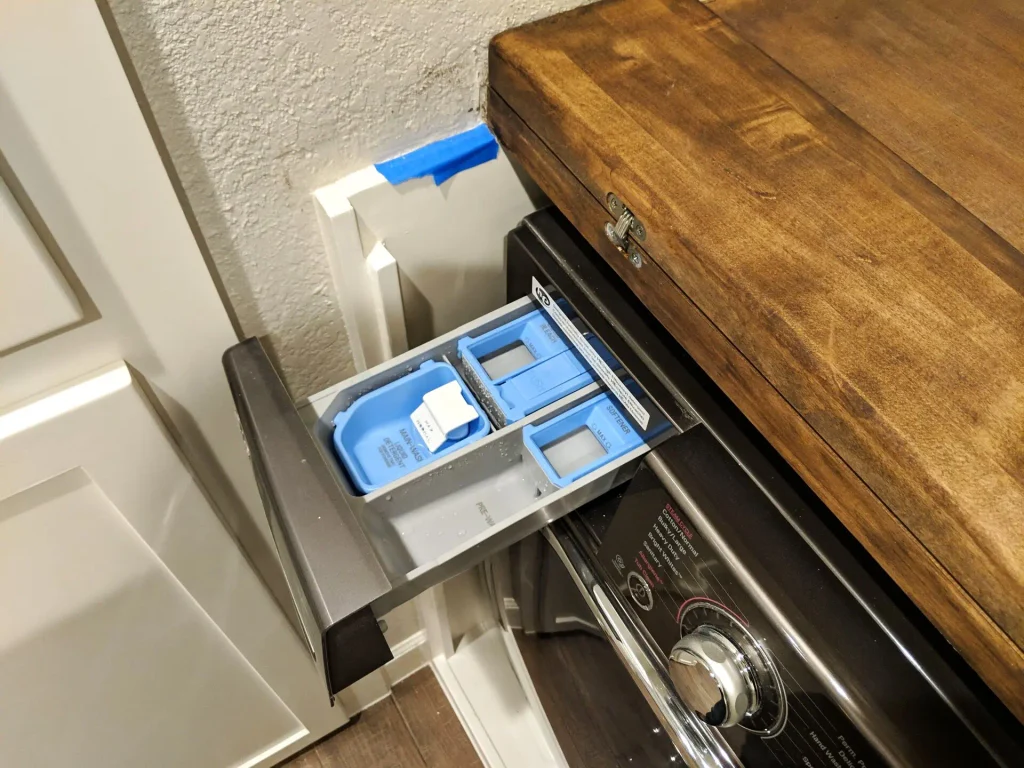 Hinged maple laundry countertop folded back for detergent access.
