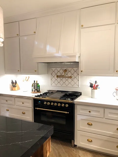 Custom range hood flanked by white cabinets with brass hardware, Huntwick Forest, Spring TX