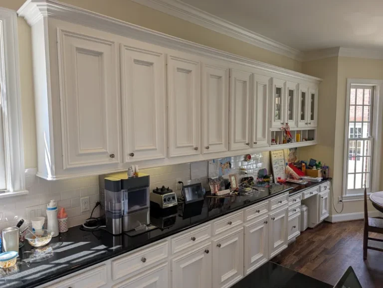 Before: long run of raised-panel cabinets with black granite counters in a West University Place kitchen