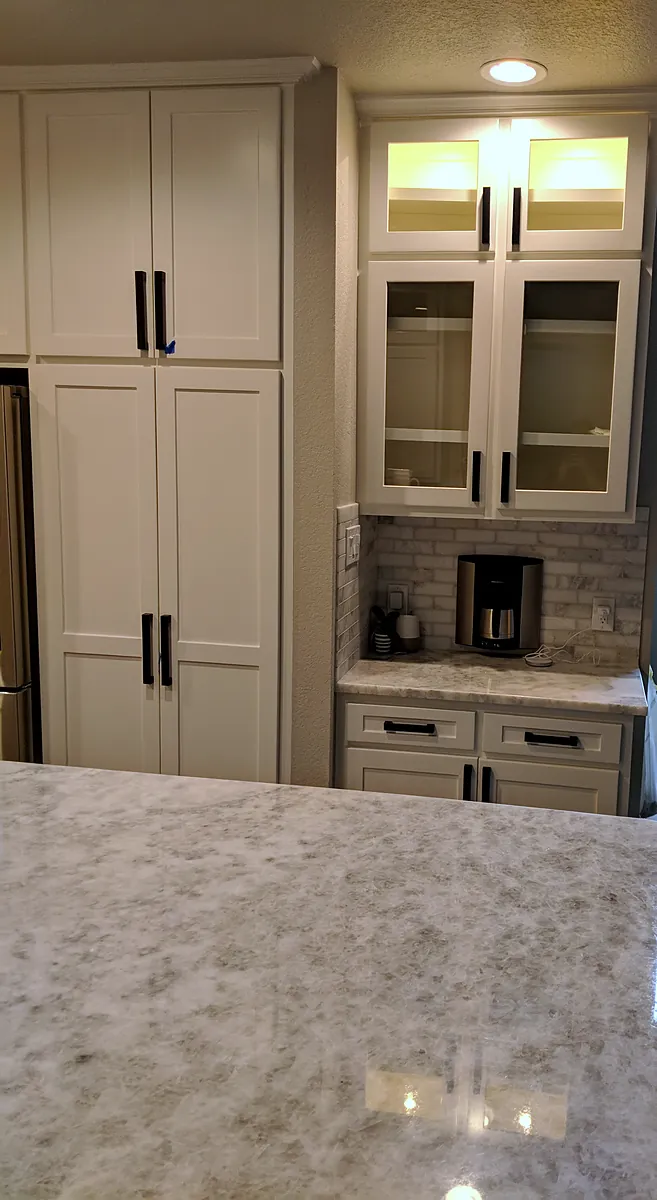 White pantry cabinets beside a coffee station with lit glass-front upper cabinets and a tile backsplash, The Parks at Cypresswood, Spring TX