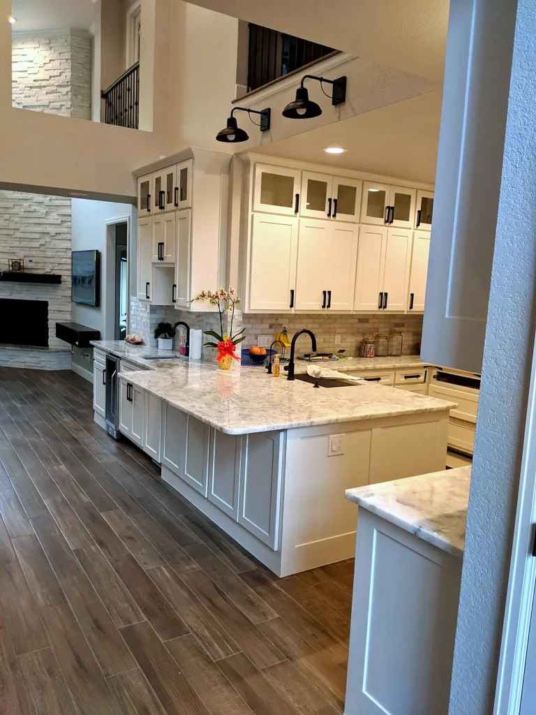 White shaker kitchen with a marble-look peninsula, black hardware, and wood-look tile floors, The Parks at Cypresswood, Spring TX