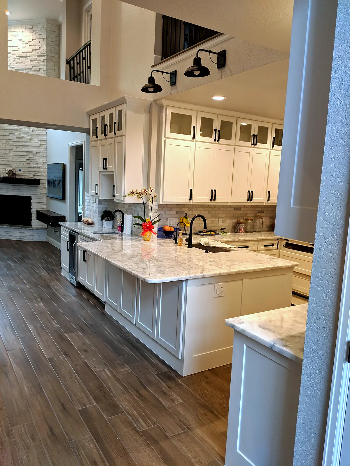 White shaker kitchen with a marble-look peninsula, black hardware, and wood-look tile floors, The Parks at Cypresswood, Spring TX