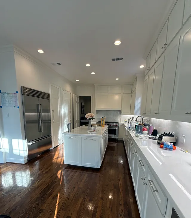 After: white shaker kitchen with cabinets to the ceiling, a new island, and a Wolf range in West University Place
