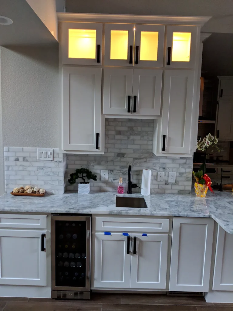 White wet bar with lit glass-front upper cabinets, a built-in wine fridge, and a stone countertop, The Parks at Cypresswood, Spring TX